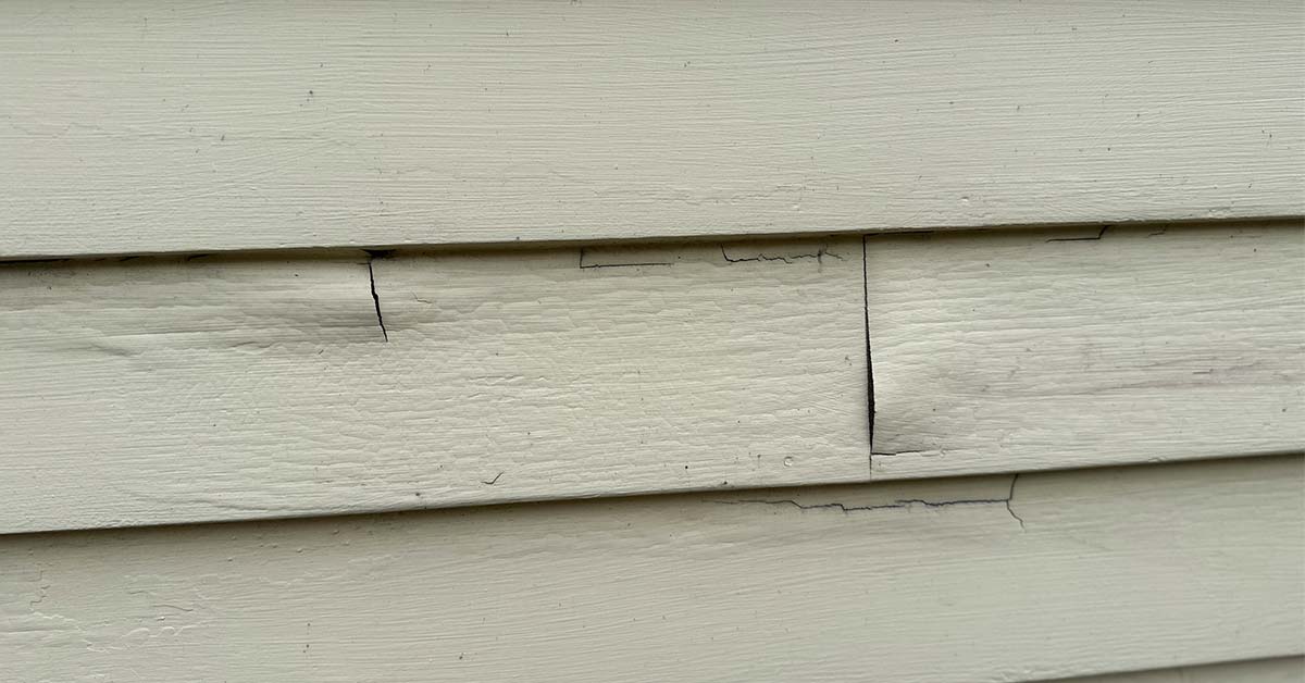Cracked and damaged exterior siding showing the need for replacement before exterior painting