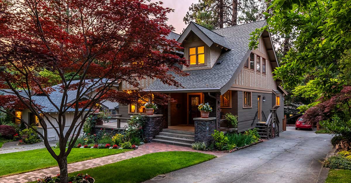 Pacific Northwest home exterior surrounded by mature trees during cool weather, showcasing the type of conditions homeowners should consider before scheduling exterior painting projects.